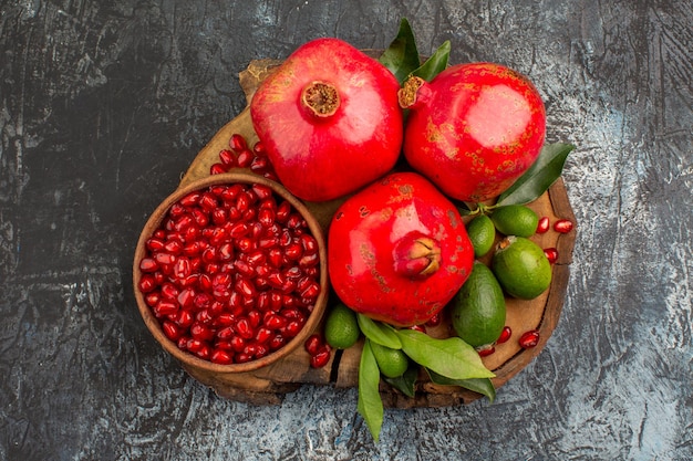 Nahaufnahme von oben Granatäpfel drei Granatäpfel und Granatapfelkerne auf dem Schneidebrett