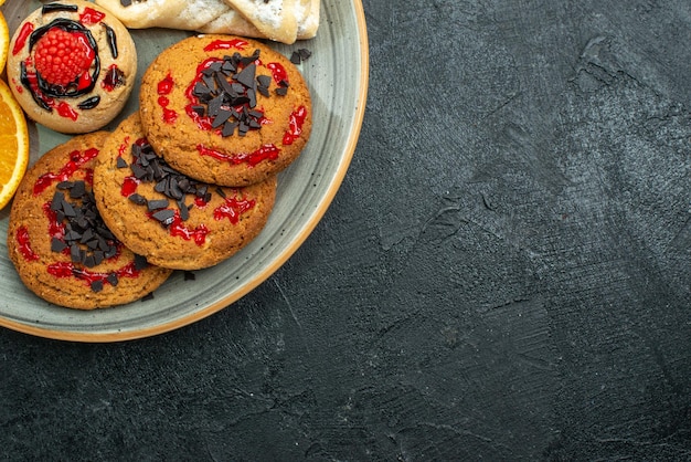 Nahaufnahme von oben leckere Kekse mit fruchtigem Gebäck und Orangenscheiben auf dunkler Oberfläche Obst süßer Kuchen Kuchen Tee Zucker