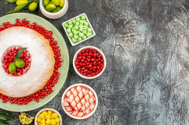 Nahaufnahme von oben Süßigkeiten ein appetitlicher Kuchen mit Samen von Granatäpfeln, Zitrusfrüchten und Bonbons