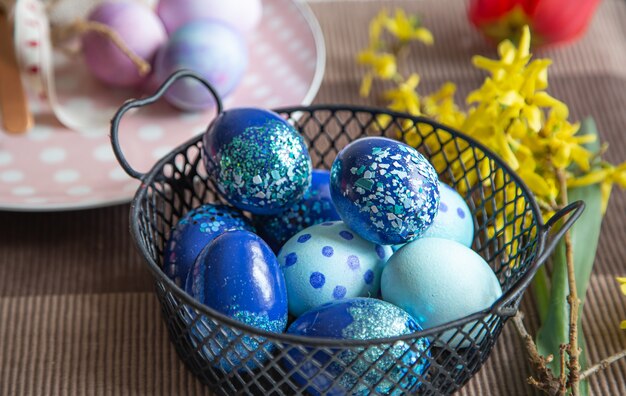 Nahaufnahme von Ostern verzierten Eiern in einem Metallkorb. Osterferienkonzept und Dekorationsideen.