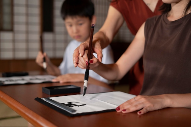 Nahaufnahme von Schülern, die japanische Kalligraphie machen, genannt Shodo