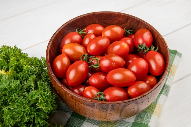 Nahaufnahme von Tomaten in der Schüssel mit chinesischem Koriander auf Stoff auf Holztisch