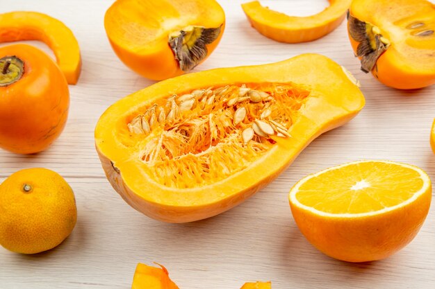 Nahaufnahme von unten Butternut-Kürbis halbieren Kaki Mandarine auf weißem Holztisch