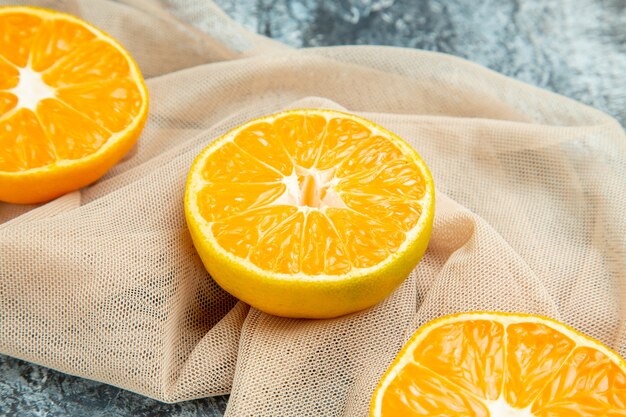 Nahaufnahme von unten geschnittene Orangen auf beigefarbenem Schal auf dunkler Oberfläche