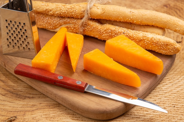 Nahaufnahme von unten Käse- und Brotmesser kleine Reibe auf Schneidebrett auf Holzoberfläche