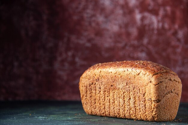 Nahaufnahme von verpacktem Schwarzbrot auf der linken Seite auf kastanienbraunem beunruhigtem Hintergrund mit freiem Platz