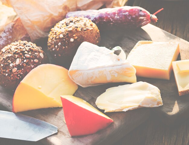 Nahaufnahme von verschiedenen Käsen auf Holztisch mit Brötchen