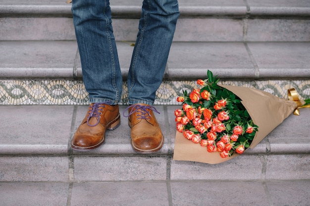 Nahaufnahme von Vintage-Schuhen mit lila Schnürsenkeln und einem Strauß Rosen