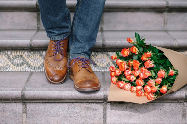 Nahaufnahme von Vintage-Schuhen mit lila Schnürsenkeln und einem Strauß Rosen