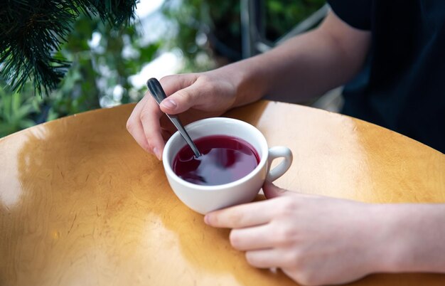 Nahaufnahme von weiblichen Händen, die eine Tasse Tee auf dem Tisch halten