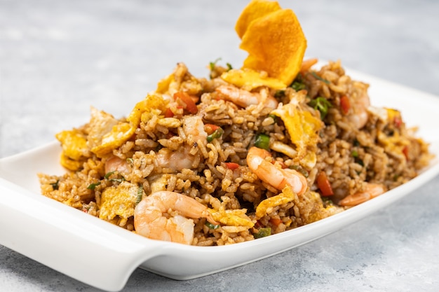 Nahaufnahme von würzigem gekochtem Reis mit Fleisch, Garnelen und Gemüse in einem Teller