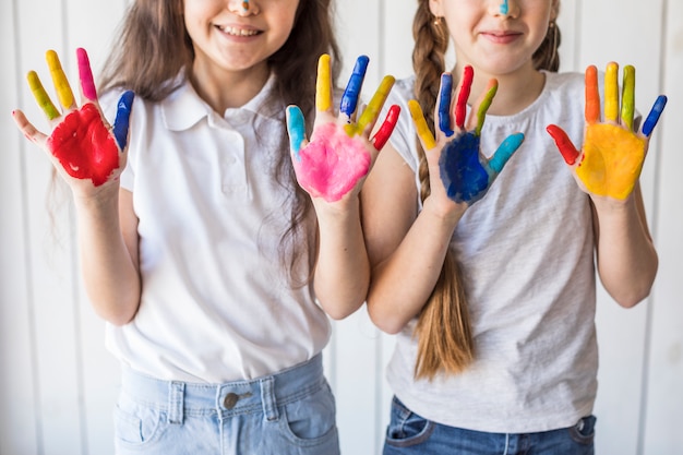 Nahaufnahme von zwei Mädchen lächelnd, die ihre gemalten Hände mit Farbe zeigen