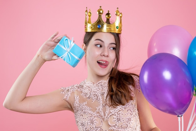 Nahaufnahme-Vorderansicht niedliches Partygirl mit Krone, die Geschenk und Luftballons hält