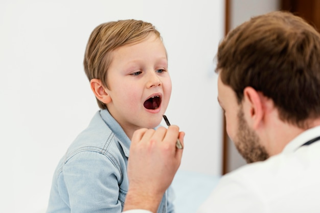 Nahaufnahmearzt, der den Mund des Kindes prüft