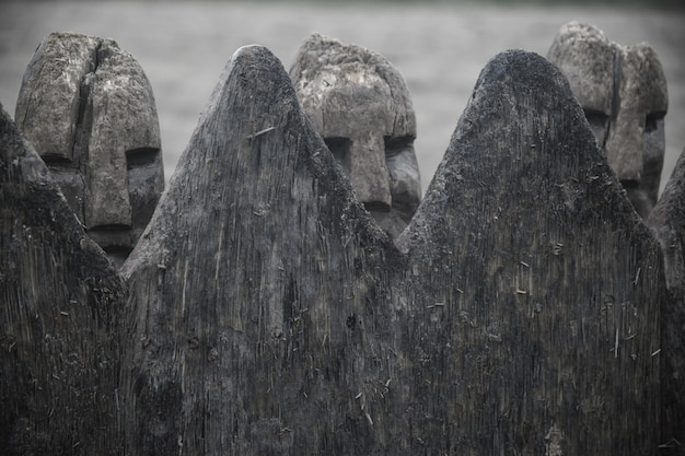 Nahaufnahmeaufnahme der alten dänischen Wikingerfiguren gemacht mit Stein hinter einem Holzzaun