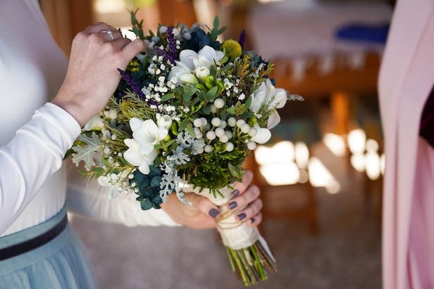 Nahaufnahmeaufnahme der Braut, die den Blumenstrauß mit schönen Blumen hält