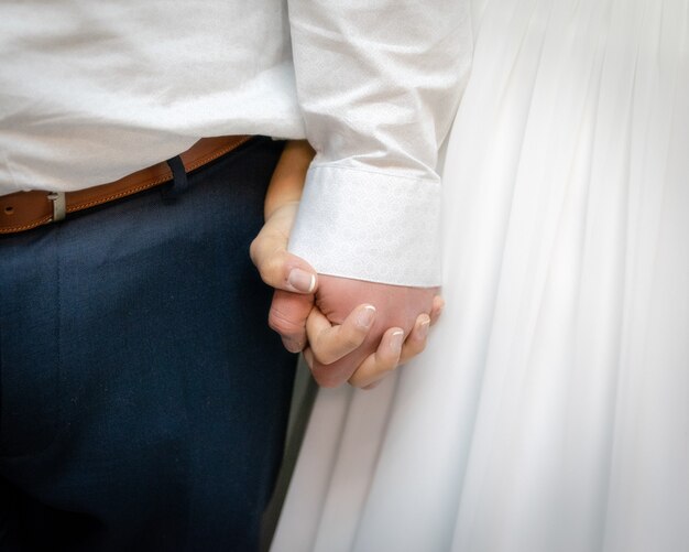 Nahaufnahmeaufnahme der Braut und des Bräutigams, die die Hände voneinander halten