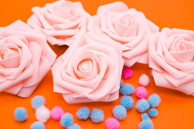 Nahaufnahmeaufnahme der rosa Rosen und der bunten Pompons lokalisiert auf orange Hintergrund