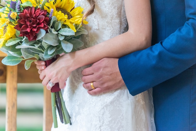 Nahaufnahmeaufnahme des Bräutigams, der die Braut von hinten bei einer Hochzeitszeremonie umarmt