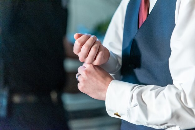 Nahaufnahmeaufnahme des Bräutigams, der sein weißes Hemd am Handgelenk anpasst