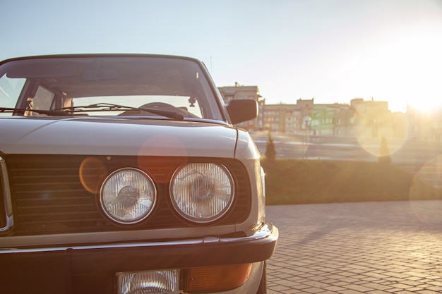 Kostenloses Foto nahaufnahmeaufnahme des runden scheinwerfers eines weißen oldtimers während des sonnenuntergangs