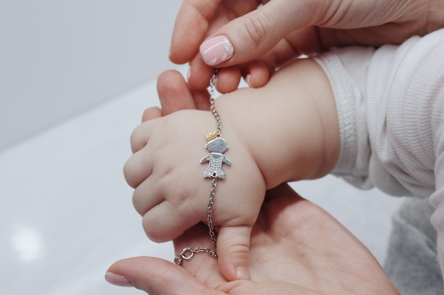 Nahaufnahmeaufnahme einer Frau, die ein niedliches Armband auf die Hand ihres Babys setzt