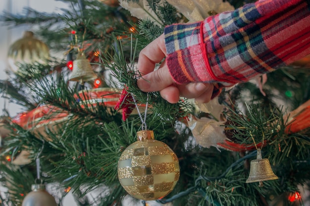 Nahaufnahmeaufnahme einer frau, die einen weihnachtsbaum mit hellen kugeln verziert