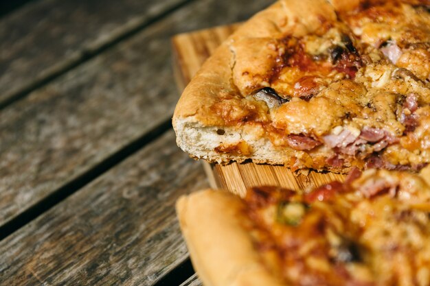 Nahaufnahmeaufnahme einer geschnittenen Pizza auf einem hölzernen Schreibtisch