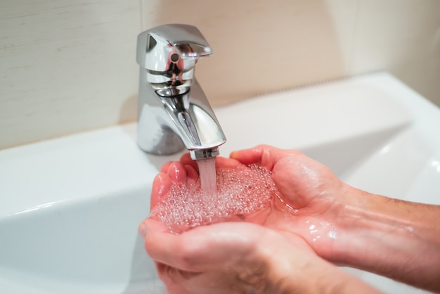 Nahaufnahmeaufnahme einer Person, die Hände im Waschbecken wäscht