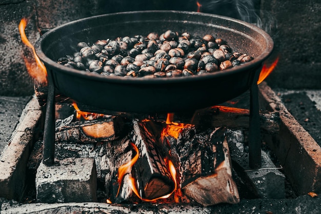 Nahaufnahmeaufnahme einer Pfanne mit Kastanien, die auf dem Feuer rösten