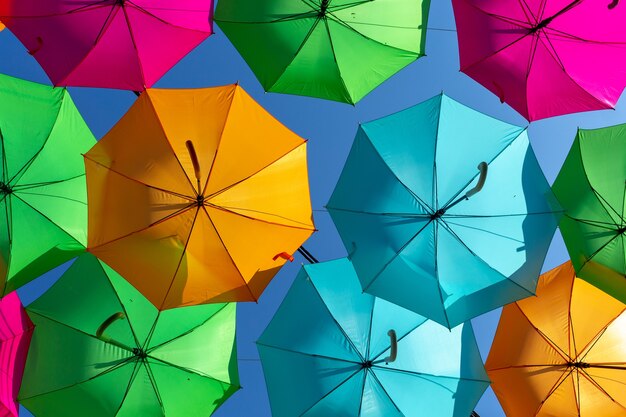 Nahaufnahmeaufnahme einer schönen Anzeige des bunten hängenden Regenschirms gegen einen blauen Himmel
