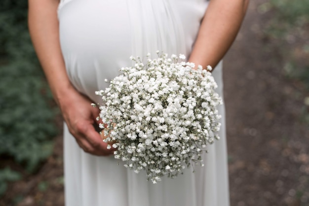 Nahaufnahmeaufnahme einer schwangeren Braut, die einen Blumenstrauß an ihrer Hochzeit hält