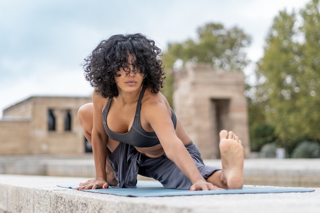 Nahaufnahmeaufnahme einer spanischen Frau praktiziert Yoga im Freien