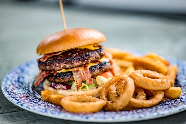 Kostenloses Foto nahaufnahmeaufnahme eines appetitlichen burgers mit zwiebelringen