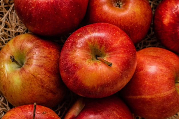 Nahaufnahmeaufnahme eines Bündels von lecker aussehenden roten Äpfeln auf einer Heuoberfläche