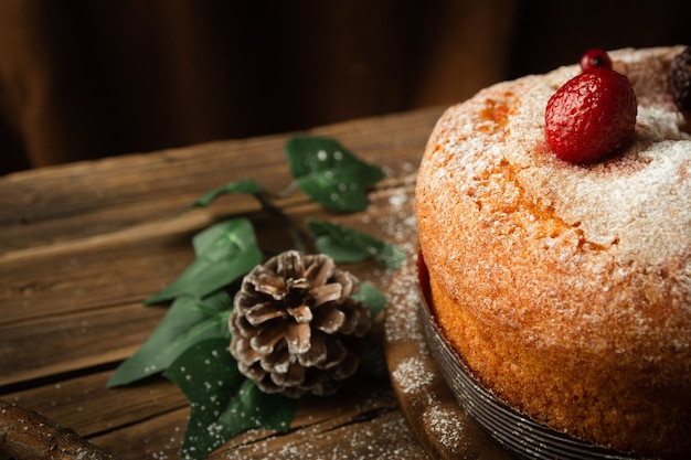 Nahaufnahmeaufnahme eines köstlichen Biskuitkuchens mit Erdbeeren, einem Tannenzapfen und Redberries auf Tisch