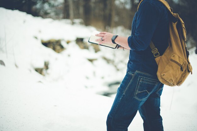 Nahaufnahmeaufnahme eines Mannes, der einen Rucksack trägt und die Bibel liest