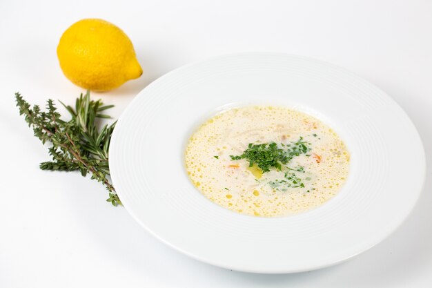 Nahaufnahmeaufnahme eines Tellers mit weißer Suppe mit Grüns