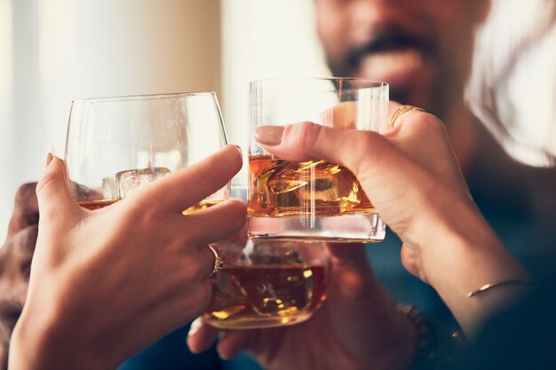 Nahaufnahmeaufnahme vieler Leute, die Gläser mit Alkohol an einem Toast anstoßen