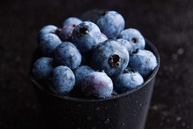 Nahaufnahmeaufnahme von Blaubeeren in einer schwarzen Schüssel mit dunklem Hintergrund