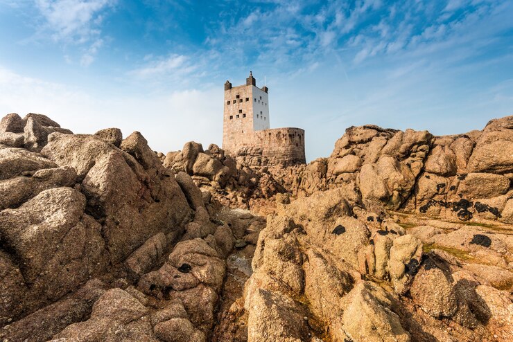 Kostenlose Foto nahaufnahmeaufnahme von klippen und felsen mit einer festung auf dem hintergrund unter einem blauen himmel