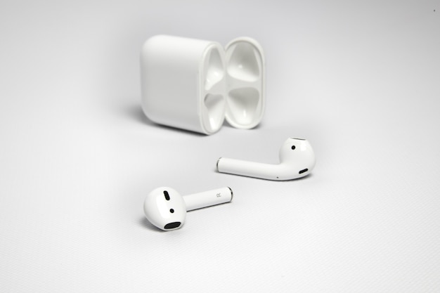 Nahaufnahmeaufnahme von weißen drahtlosen Kopfhörern mit ihrem Fall auf weißem Hintergrund