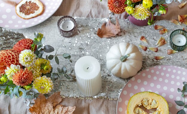 Nahaufnahmedetails des Dekors eines festlichen Herbsttisches, Blumen, Kerzen und Kürbisse.