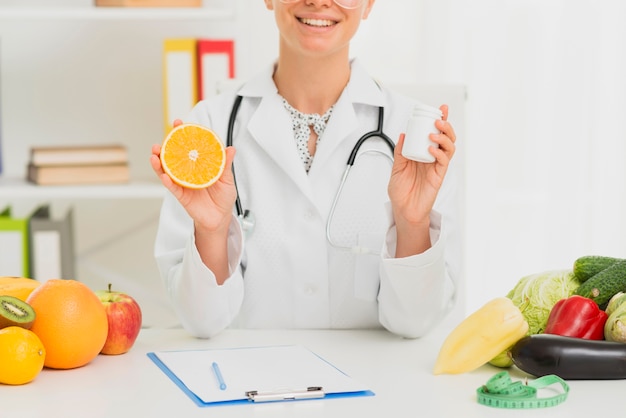 Kostenloses Foto nahaufnahmedoktor, der eine halbe orange hält