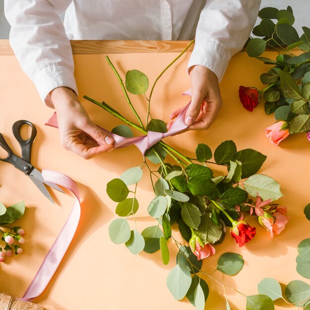 Nahaufnahmeflorist, der ein Band für Blumenstrauß macht