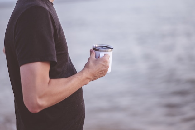 Nahaufnahmefokusaufnahme eines Mannes, der einen weißen Becher hält