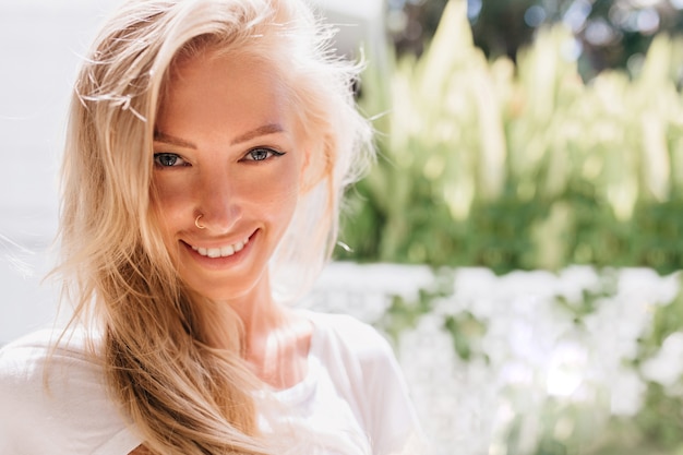 Nahaufnahmefoto der lächelnden Frau mit durchbohrter Nase. Porträt der lächelnden romantischen blonden Dame