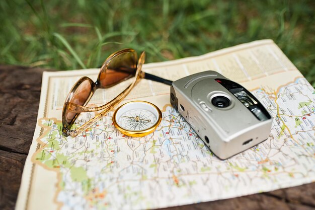 Nahaufnahmefoto des Kompasses, der auf der Karte neben der Kamera und der Sonnenbrille liegt