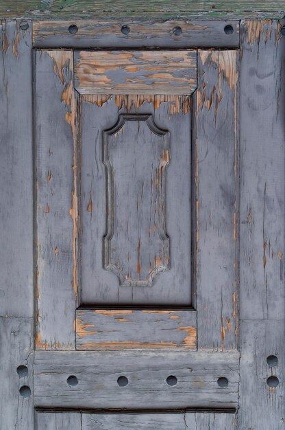 Nahaufnahmefoto einer alten Holztür mit abblätternder grauer Farbe