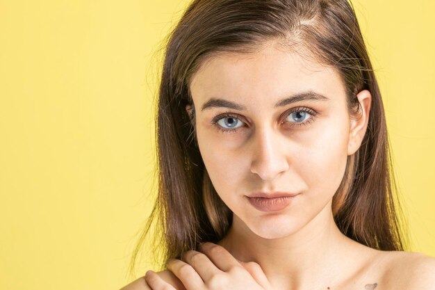 Nahaufnahmefoto einer jungen Dame auf gelbem Hintergrund, die in die Kamera schaut Foto in hoher Qualität